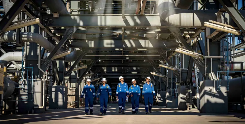 Five men in a row with blue overalls and white hard hats