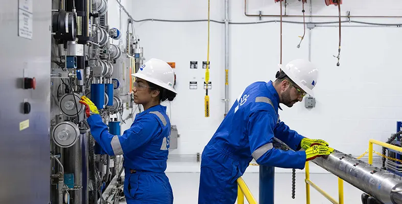 Electris well completions make it possible for operators to get more out of their assets with fewer requirements for costly well interventions. (Image source: SLB) Female_and_male_engineer_with_well_completions_equipment