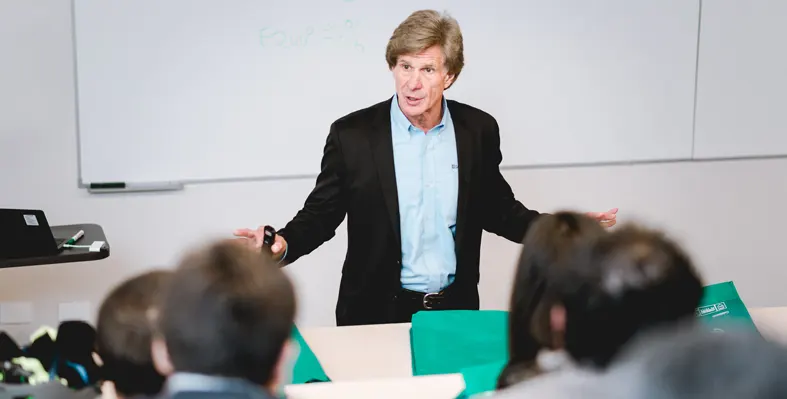 Man teaching a class with whiteboard in the background