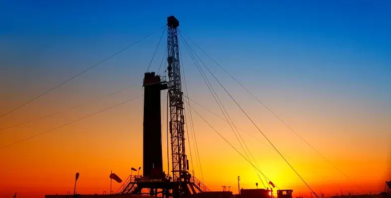 Oil rig set against sunset sky