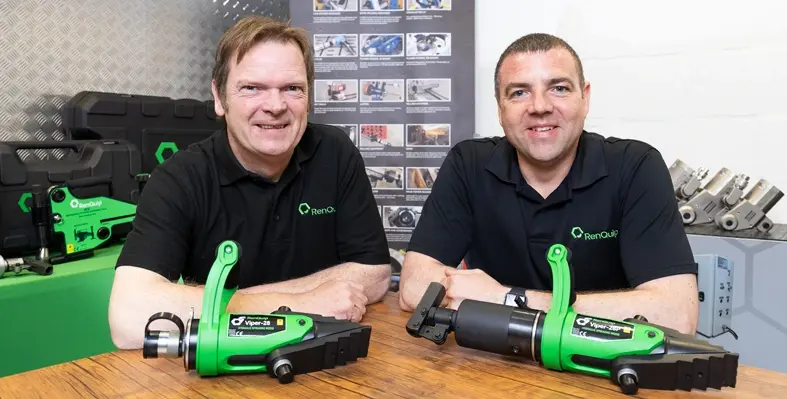 John Morgan and Marc Gerrard, RenQuip directors launching the company's groundbreaking flange spreading technology. (Image source: Renquip) Two men sitting at table with mechanical equipment.