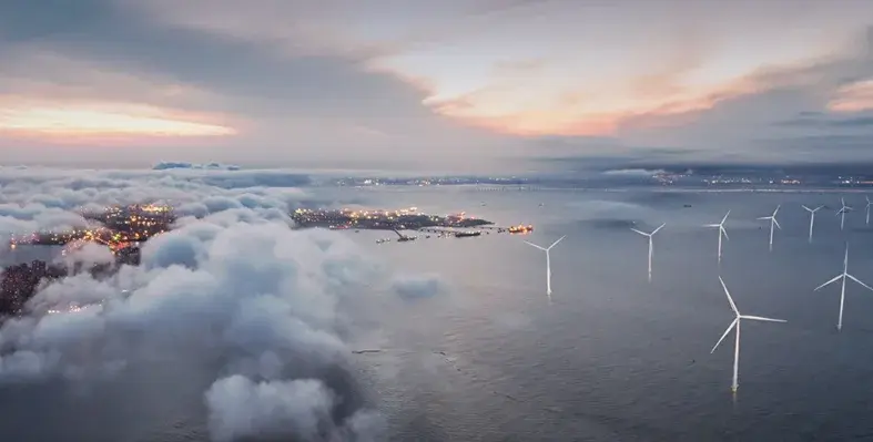 Wind turbines amidst clouds and sea